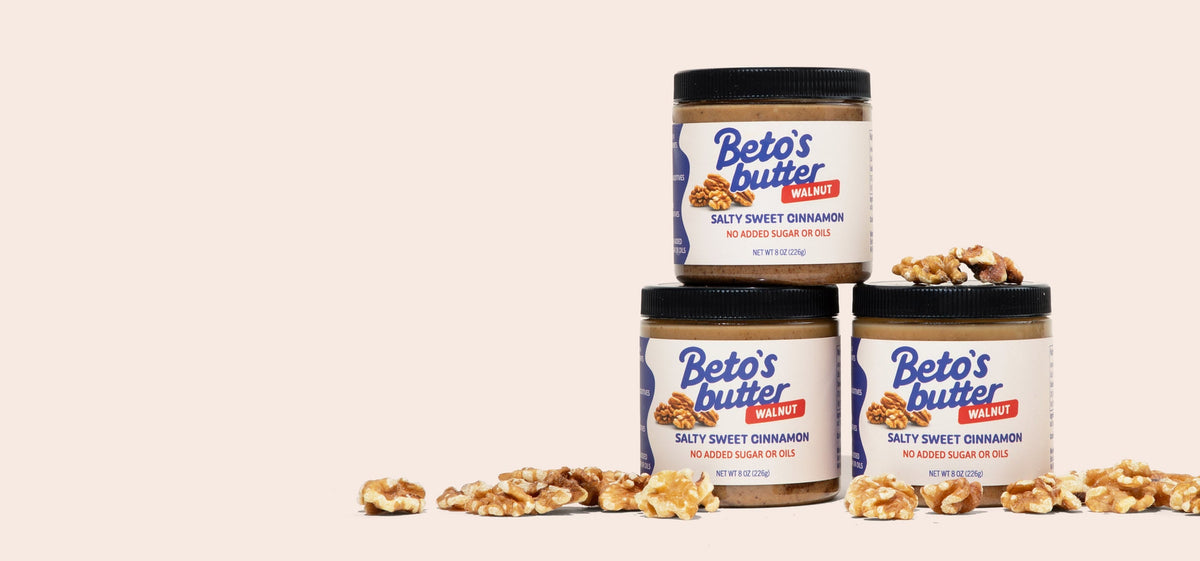 3 jars of Beto's Butter Salty Sweet Cinnamon Walnut Butter stacked with walnuts scattered