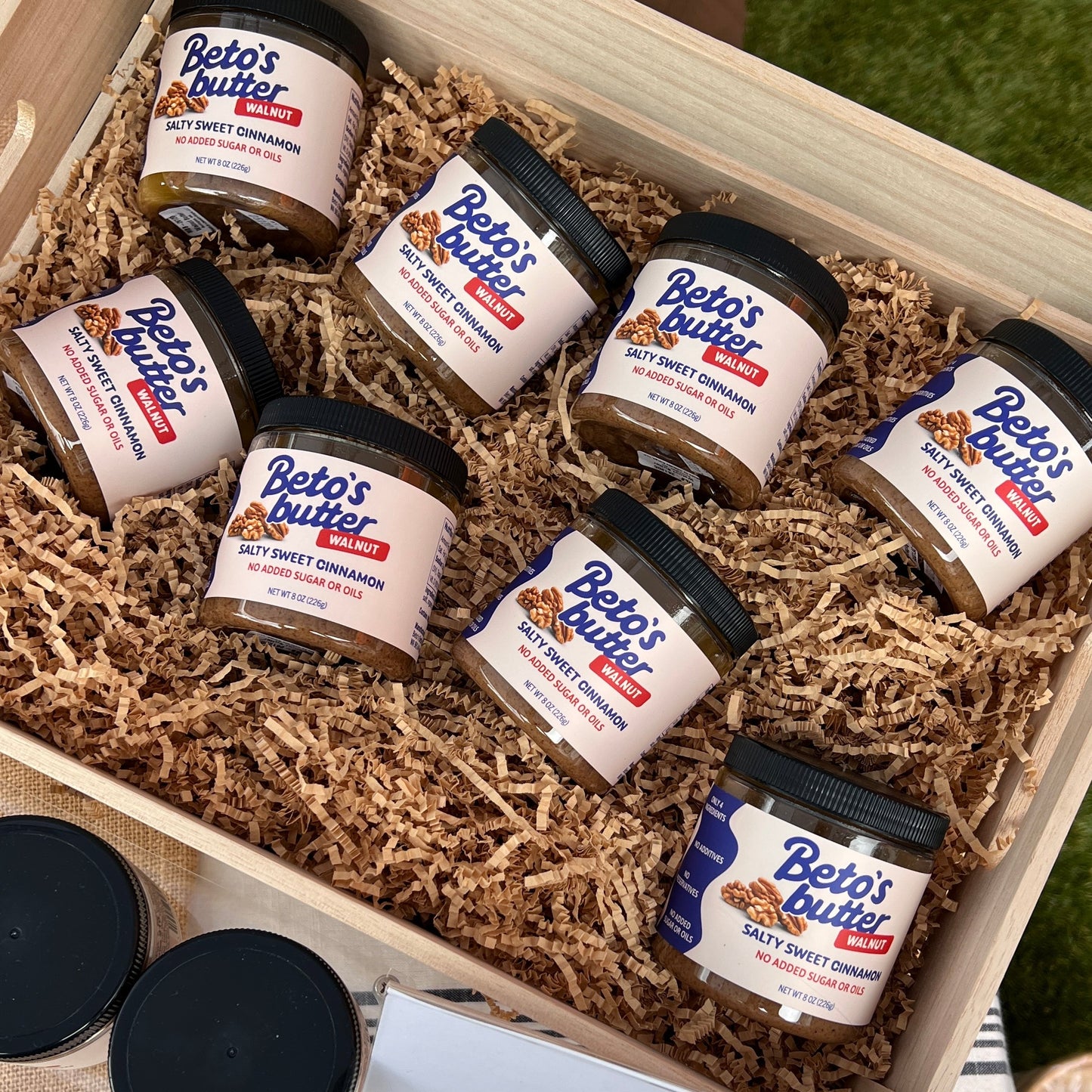 Beto's Butter jars displayed in a wooden crate with shredded brown paper packing